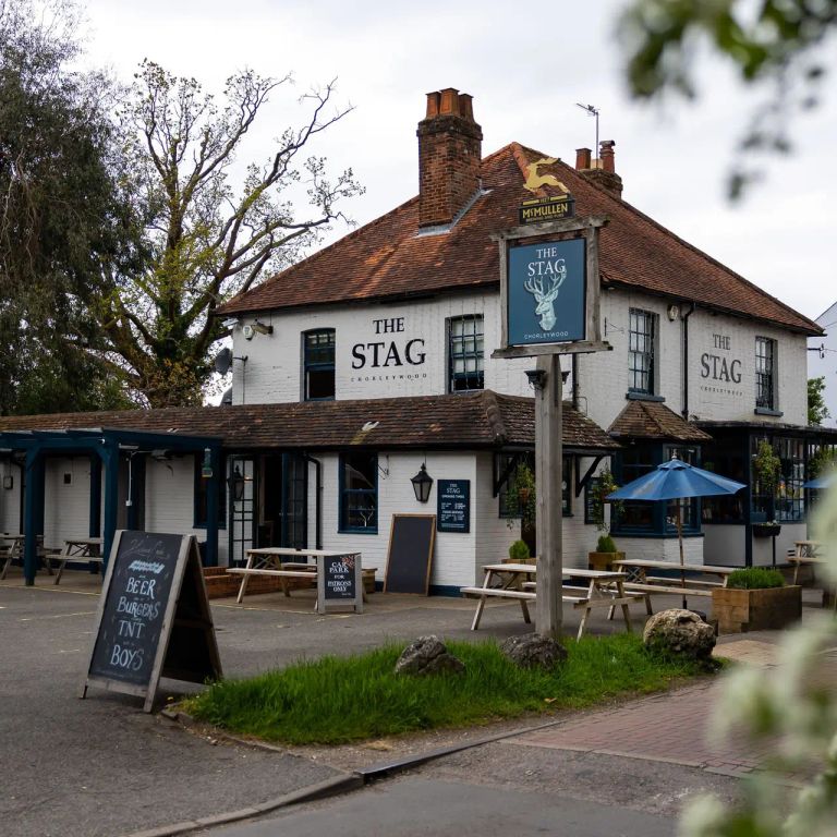 The Stag pub, a white building with a brown roof, outdoor seating, and a prominent deer sign.